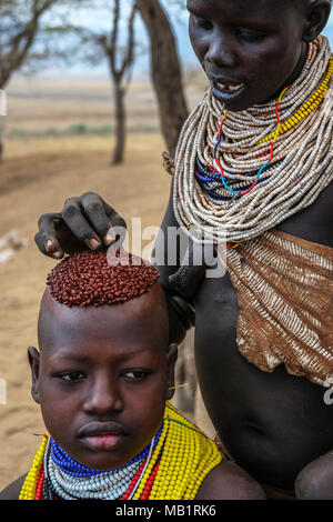 Omo Valley, Ethiopia - January 26, 2018: Unidentified woman of the Karo tribe with traditional jewelry and her son in Omo valley, Ethiopia. Stock Photo