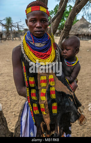 Omo Valley, Ethiopia - January 26, 2018: Unidentified woman of the Karo tribe with traditional jewelry and her son in Omo valley, Ethiopia. Stock Photo