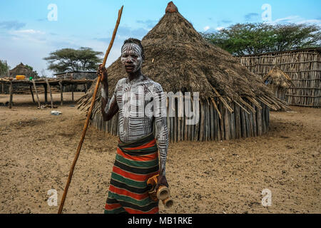 Omo Valley, Ethiopia - January 26, 2018: Unidentified Karo Man with village in the background in Omo Valley, Ethiopia. Stock Photo