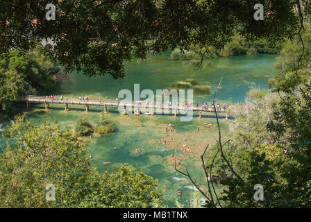 People on a footbridge over a lake seen from above at Krka, Croatia