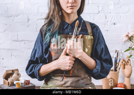 cropped image of female artist holding brushes  Stock Photo