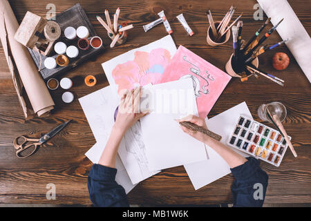 top view of female artist painting sketches at workplace with paints and brushes Stock Photo