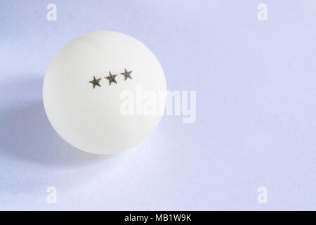 A ping-pong ball with three stars on a light blue background Stock Photo
