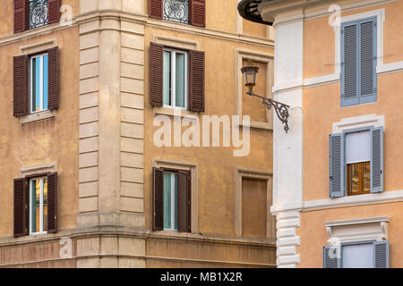 Windows and wooden shutters on the terracotta coloured walls of buildings on the corner of a street  in Rome, Italy. Stock Photo