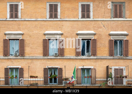 A building overlooking the Piazza Navona in Rome, Italy. The Italian flag features a shield divided into four squares each representing one of the mar Stock Photo