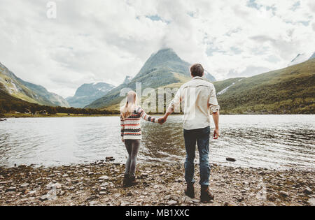 Couple man and woman walking together holding hands enjoying mountains and lake outback nature view family traveling adventure lifestyle concept vacat Stock Photo