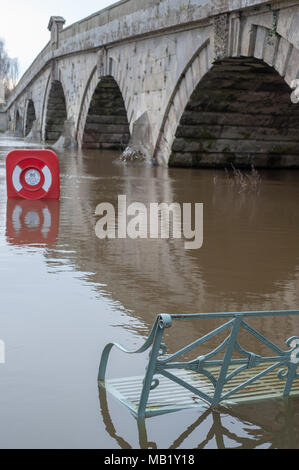Bench on the riverbank at Atcham's Mytton and Mermaid hotel inundated by flood waters from the River Severn Stock Photo