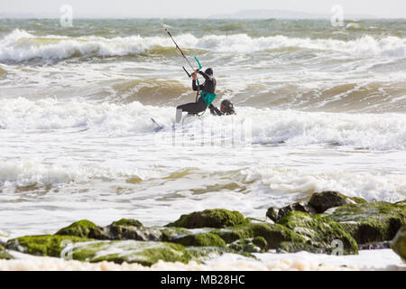 Sandbanks, Poole, Dorset, UK. 6th April, 2018. UK weather: breezy day at Sandbanks as kite surfers make the most of the windy conditions - kite surfer who has got separated from his board gets a lift back to shore! kitesurfers kite surfers kite surfer kiteboarders kite boarders kitesurfer kitesurfing kite surfing kiteboarding kite boarding kiteboarder kite boarder  Credit: Carolyn Jenkins/Alamy Live News Stock Photo