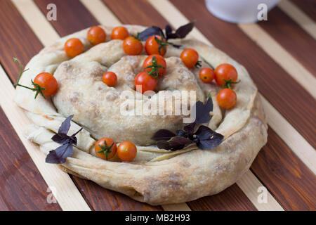 spiral filo pie burek with cherry tomatoes on wooden table Stock Photo