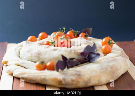 spiral filo pie burek with cherry tomatoes on wooden table Stock Photo