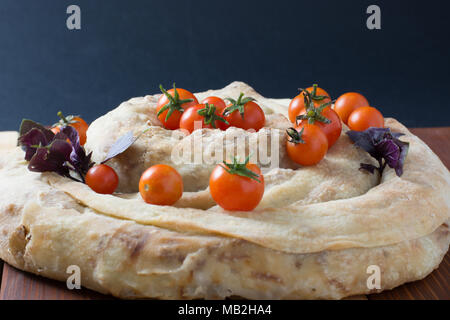 spiral filo pie burek with cherry tomatoes on wooden table Stock Photo