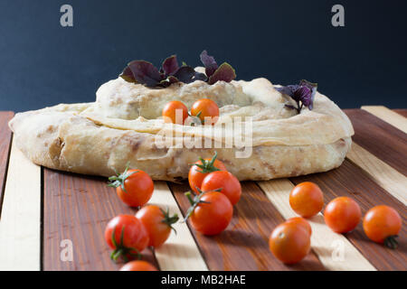 spiral filo pie burek with cherry tomatoes on wooden table Stock Photo