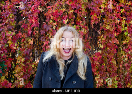 Happy smiling blond with leaves on background Stock Photo