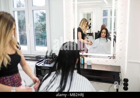 Portrait of young woman sitting at hairdresser salon having hair cut Stock Photo