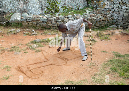 Lovemore, a guide, sketches out the shape of the Zimbabwe bird at Great Zimbabwe near Masvingo in Zimbabwe. Stock Photo