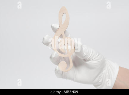 Hand in white glove holding Wooden treble clef sign isolated on white background Stock Photo