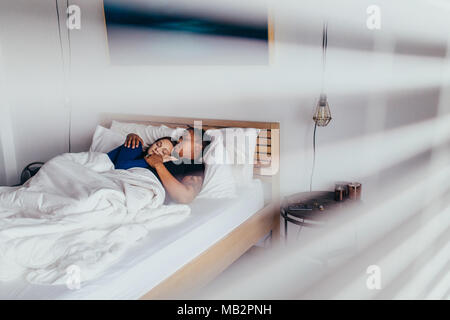 Interracial young couple hugging while sleeping on bed. Man and woman sleeping peacefully in bedroom. Stock Photo