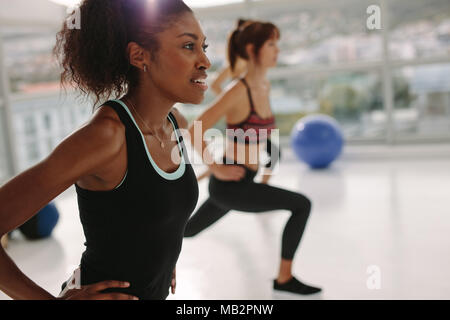 African young woman exercising in gym class. Stretching workout session in health center. Stock Photo