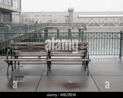 Front of bench outside on a wet, foggy day sitting on a pier Stock Photo