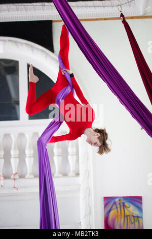 Young attractive woman hangs upside down on the aerial silk Stock Photo