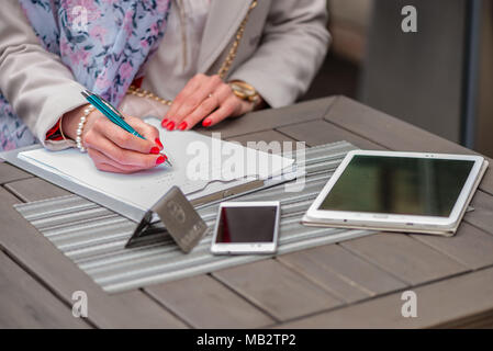 Close-up of female hands. Woman writing something sitting at cafe. Signing documents. Stock Photo