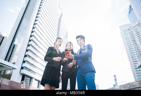 Surprised business people using smart phone outdoors . excited young businessman and business woman expressing positive while standing outdoors with o Stock Photo