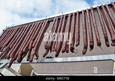 Homemade sausages of pork smoked and dried stand on the table for sale. Stock Photo