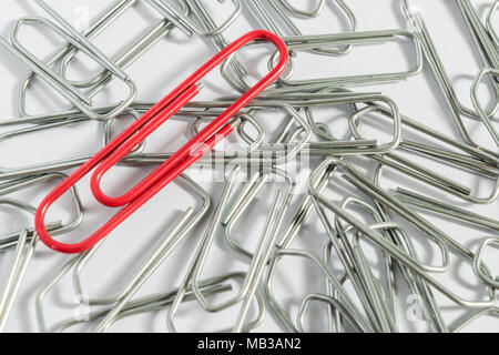 A red clip in a bunch of metallic clips Stock Photo