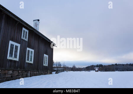 Old - traditional - house in rural sweden and a wintery landscape on a beautiful winters day, at dusk. Stock Photo