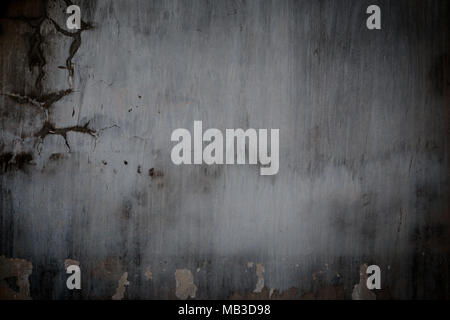 Weathered and aged dark gray concrete wall with stains and paint partly peeled off with vignette Stock Photo