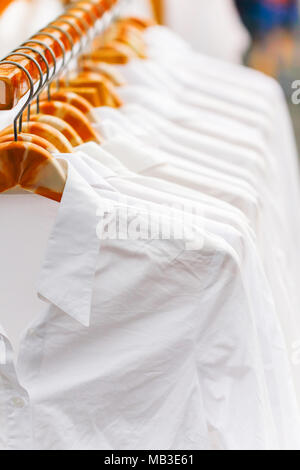 Crease white shirts hanging on rack in a row, Selective focus Stock Photo