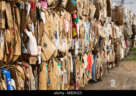 Bundles of baled cardboard are stacked and waiting for recycling. Stock Photo