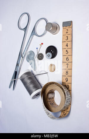 black and white thread coils, scissors, pin and tape measure on white ...