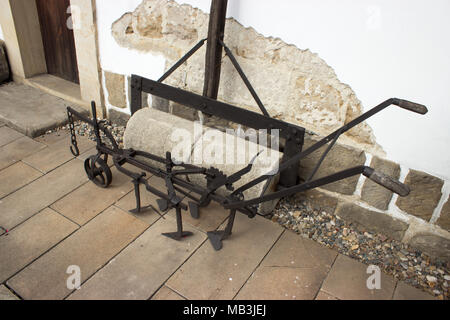 Old line making machine for planting crops in the field and cylinder. Machines are standing on the pavement. Stock Photo