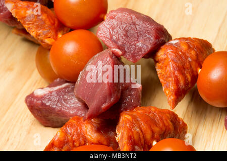 Cubed, raw wild boar, chorizo sausage and cherry tomatoes about to be grilled. Wild boar meat is much darker than domestic pork and tastes very differ Stock Photo