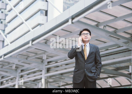 business, technology and people concept - serious businessman with smartphone talking over office building Stock Photo