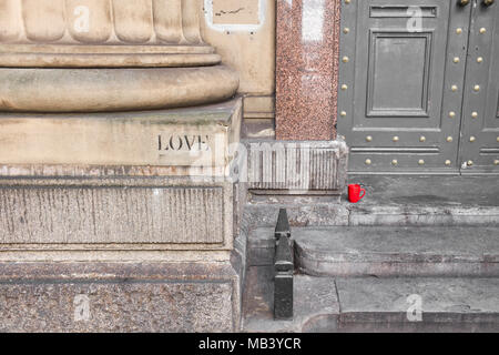 Red mug on a doorstep with the word love stencilled on stonework Stock Photo