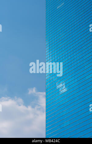 Blue office glass building and blue sky with a cloud - vertical photo. Skyscraper and the sky divide the frame into two symmetrical halves Stock Photo