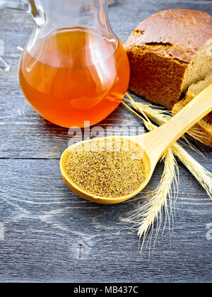 Malt in a spoon, bread, kvass in a glass jug and spikelets on the background of wooden board Stock Photo