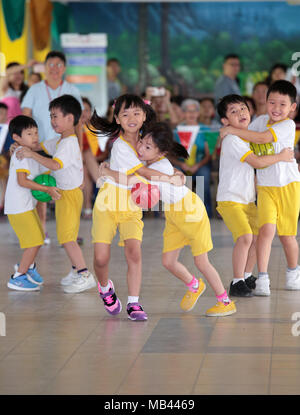 Children are playing hug the ball teamwork game during their kindergarten sport day. Stock Photo