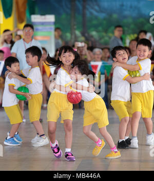 Children are playing hug the ball teamwork game during their kindergarten sport day. Stock Photo