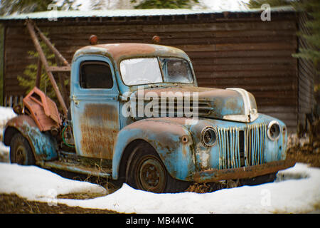 An old, blue 1946 Ford tow truck, on the side of a barn, in Noxon, Montana. Stock Photo