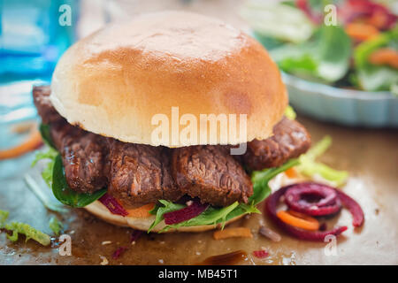 Bun with barbecue beef brisket and mixed leaves salad Stock Photo