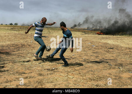 Gaza, Palestine. 6th Apr, 2018. Palestinian youths playing football, during clashes with Israeli security forces on the Gaza-Israel border following a protest, east of Khan Yunis, in the southern Gaza Strip on April 6, 2018. Clashes erupted on the Gaza-Israel border a week after similar demonstrations led to violence in which Israeli force killed 19 Palestinians, the bloodiest day since a 2014 war. Credit: Awakening Photo Agency/Alamy Live News Stock Photo