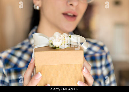 Woman hands holding  gift box human face out of focus in background Stock Photo