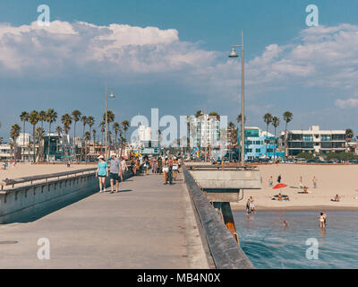 People walk on the pier and sunbathe on the beach. View from Venice Beach Pier. Stock Photo