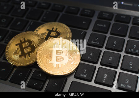 Bitcoin cryptocurrency coins lying on laptop keyboard, blurry background Stock Photo