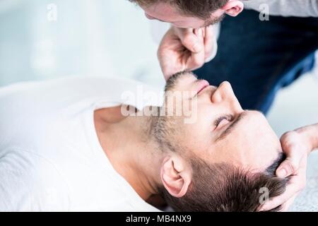 MODEL RELEASED. First aider checking if an unconscious man is breathing. Stock Photo