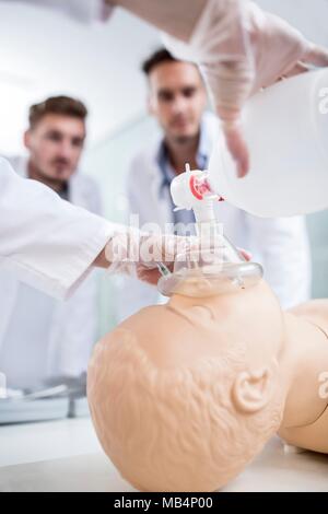MODEL RELEASED. Doctor practising bag-valve-mask ventilation on a training dummy. Stock Photo