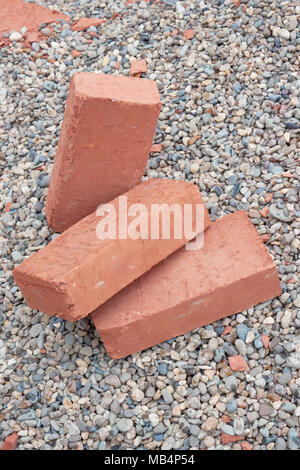Three red clay bricks lying on the gravel Stock Photo